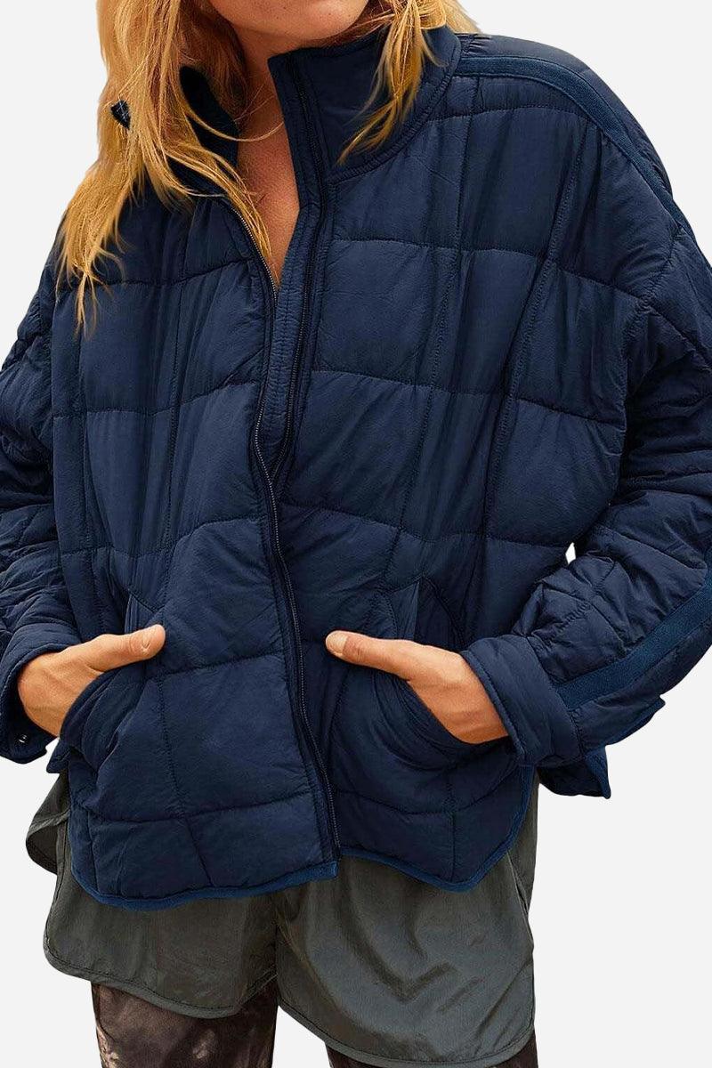Navy blue lightweight puffer travel jacket with quilted design and front pockets worn by woman
