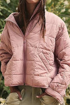 Lightweight pink puffer travel jacket with front zipper and pockets, perfect for versatile and comfortable outdoor wear