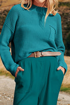 Woman wearing peacock blue relaxed knit sweater top and high-waisted trousers illustrating European minimalism style