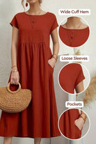 Rust red capped-sleeve voluminous pleated midi dress with loose sleeves, wide cuff hem, and pockets, styled with a round neck and breathable fabric.
