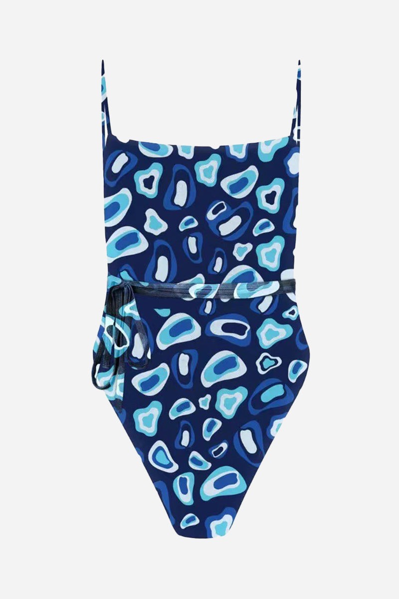 Tan-through open back one piece swimsuit in blue abstract pattern with adjustable straps and side tie detail