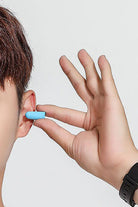 Person inserting blue foam earplug, part of Travel Comfy Kit for noise reduction during travel