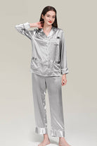 Woman wearing silver long sleeve silk pajamas button-up top and matching pants