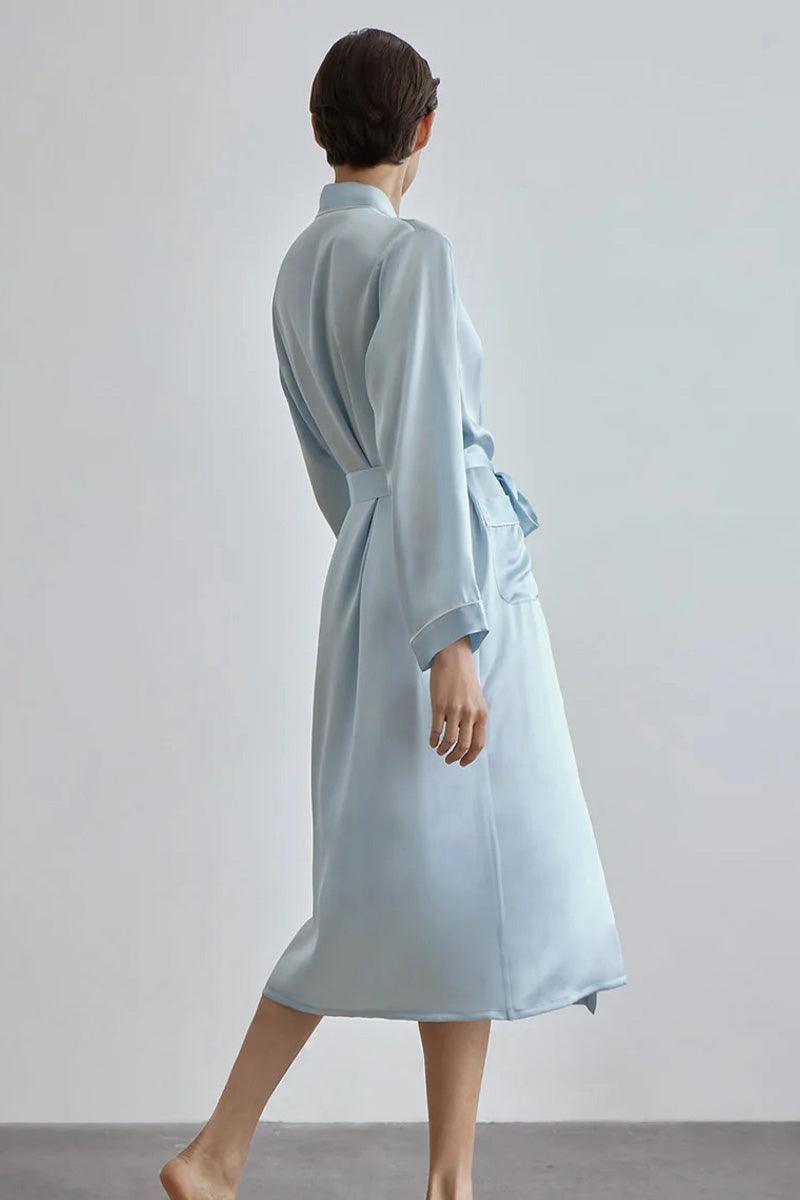 Back view of a woman wearing a light blue Mulberry Silk Nightgown with sash belt, long sleeves, and relaxed fit