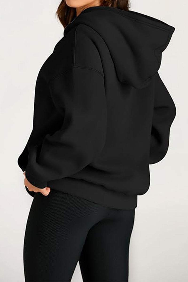 Woman wearing a black oversized fleece-lined hoodie with a relaxed fit and hood.