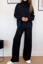 Woman wearing black knitted turtleneck two-piece set with wide-leg pants and white sneakers indoors