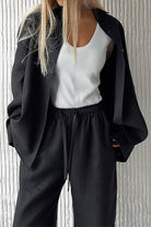 Woman wearing black 100% cotton Wanderlust two-piece set with white tank top.