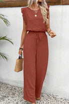 Woman wearing an elegant two-piece set in rust color with lace detail, featuring a sleeveless top and wide-leg pants.