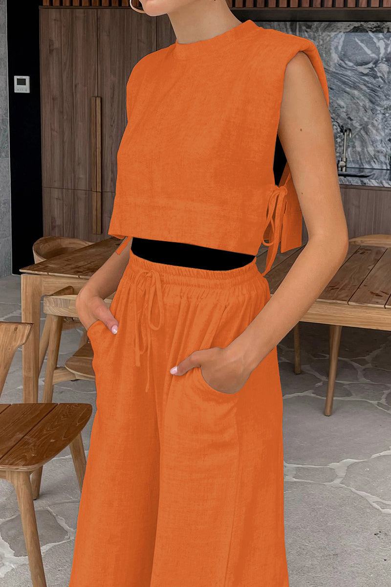 Woman wearing orange breathable cotton-linen blend sleeveless two-piece outfit with relaxed fit pants and crop top indoors