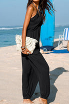 Sunshine On Sand black halter-neck jumpsuit with wide legs and elastic ankle cuffs on beach model