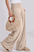 Woman wearing oversized linen blend palazzo pants and holding a woven handbag, part of the Oversized Linen Leaved-IN Set.