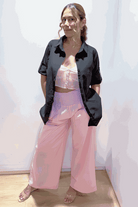 Woman wearing oversized linen-leaved-in set with black linen-blend shirt and pink palazzo pants, standing against white background