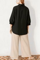 Woman wearing black oversized linen blend shirt and beige palazzo pants from Oversized Linen Leaved-IN Set side view