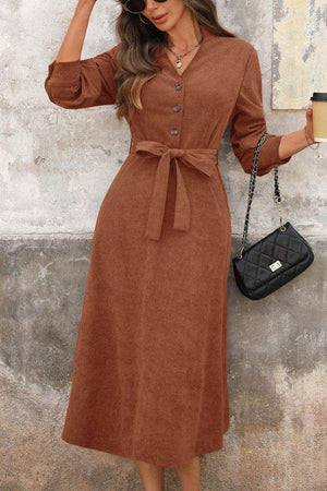 Effortlessly polished corduroy tie-waist midi dress in brown with button front and long sleeves, styled with black handbag and coffee cup.