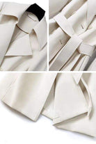 Close-up details of timeless retro belted trench coat showing collar, adjustable waist belt, and smooth structured fabric in beige.