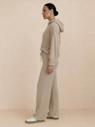 Woman wearing a beige waffle-knit two-piece set with hoodie and wide-leg pants standing sideways