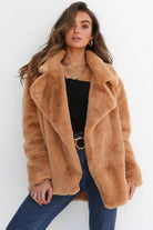 Woman wearing tan open front oversized faux fur jacket with draped shawl collar and mid-hip length