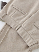Close-up of beige thermal wool blend trousers with elastic back waist and tailored pockets.