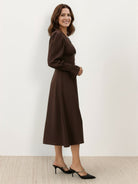 Woman wearing slimming V-neck midi dress with button-front and ruffle cuffs, standing outdoors