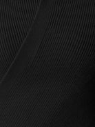 Close-up of slim fit asymmetric wrap ribbed knit top with diagonal button closure and flared cuffs