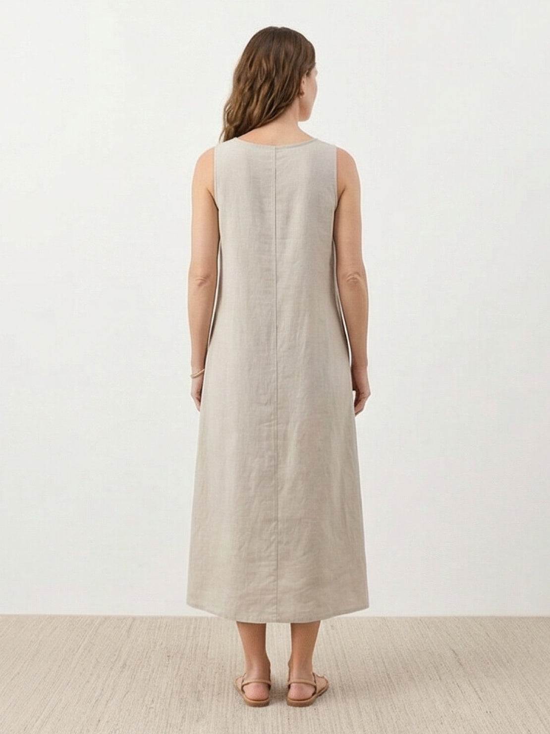 Woman wearing a lightweight cotton linen sleeveless maxi dress with a round neckline and flowing ankle-length silhouette
