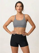 Woman wearing a criss-cross back three-piece tankini set with printed sports bra and boy shorts under a loose solid tank top