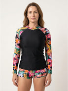 Woman wearing tropical print rash guard set with long sleeves and boy-cut shorts in matching floral design