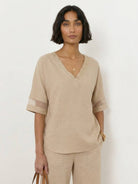 Mature woman wearing lightweight linen top with V-neck and button detail in light khaki