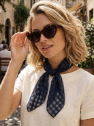 Lightweight 100% linen neck scarf with timeless checkered pattern and natural rolled edges, styled around the neck.