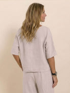 Woman wearing light beige short-sleeved pullover and wide trouser matching set from the back