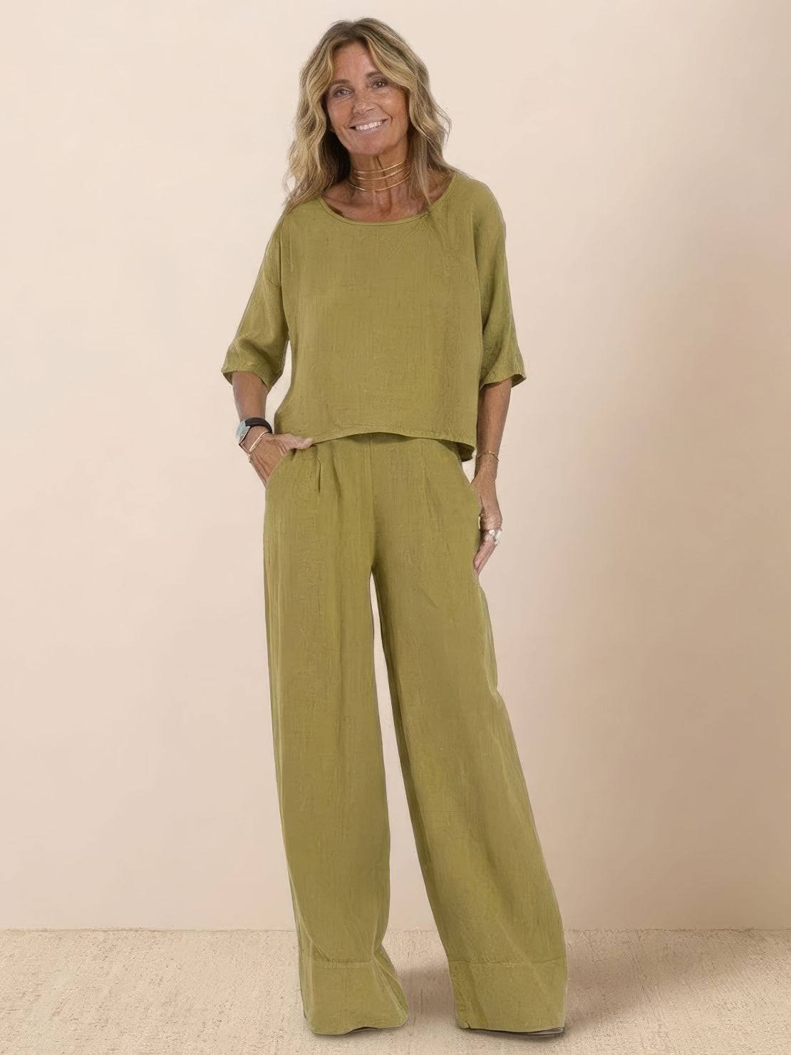 Woman wearing olive green short-sleeved pullover and wide trouser matching set against beige background