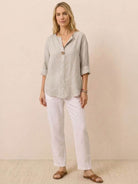 Woman wearing a pure linen age-defying button detail shirt and white pants, styled for comfort and elegance
