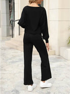 Woman wearing black round neck loose fit cozy two-piece set with wide-leg pants and white sneakers outdoors