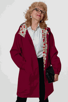 Woman wearing burgundy Rain Couture Windbreaker with floral inner lining and black purse