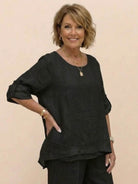 Woman wearing black asymmetrical two-piece trouser set with rolled-up sleeves and loose fit