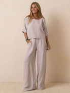 Woman wearing a beige short-sleeved pullover and wide trouser matching set in lightweight cotton fabric.