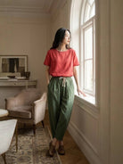 Woman wearing breezy relaxed fit straight pants sitting casually against a wall