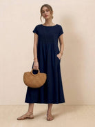 Woman wearing capped-sleeve voluminous pleated midi dress with flowing skirt and pockets