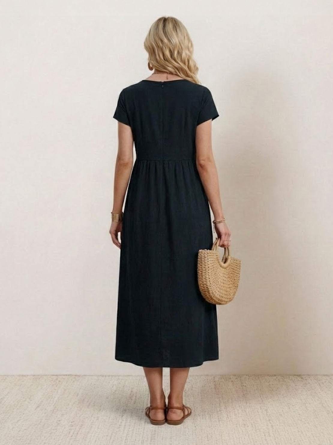 Woman wearing capped-sleeve voluminous pleated midi dress with flowing skirt and pockets