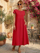 Woman wearing capped-sleeve voluminous pleated midi dress with flowing skirt and pockets