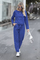 Woman wearing blue cotton-linen monochrome capsule set with longline top and wide-leg pants walking outdoors with white sneakers and handbag