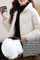 Woman wearing light beige Everyday Warmth Coat with hood and holding a coffee cup, highlighting 5-layer thermal insulation detail