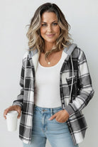 Woman wearing a Highland Plaid Shacket with gray and white plaid, a hood, and button-front closure, styled casually with jeans and a white top.