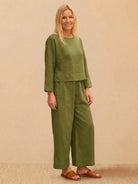 Woman wearing olive green loose solid color two-piece set with long sleeves and wide-leg pants