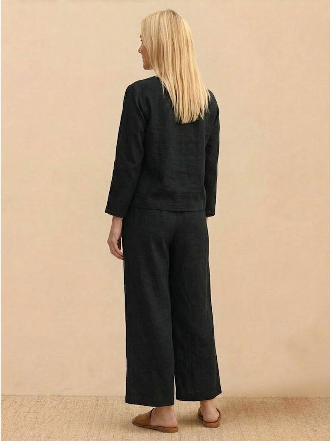 woman wearing loose solid color black two-piece set with long sleeves and wide-leg pants standing back view