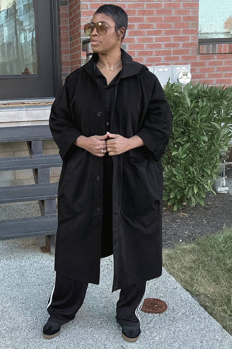 One-size oversized black Heritage Windbreaker Jacket with attached hood and large front pockets worn outdoors