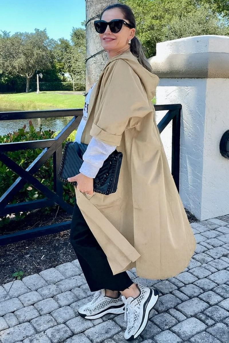 Woman wearing oversized beige Heritage Windbreaker Jacket with hood and longline cut outdoors.