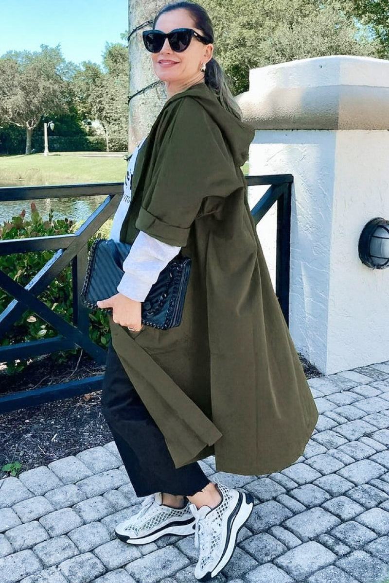 Woman wearing oversized olive green Heritage Windbreaker Jacket with hood and snap buttons outdoors