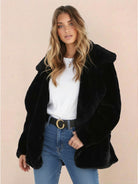 Woman wearing black open front oversized faux fur jacket with shawl collar and casual jeans