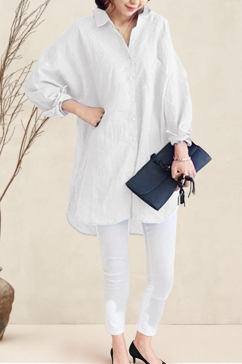 Woman wearing oversized linen shirt in white with rolled-up sleeves, paired with white pants and black heels, holding a black clutch.